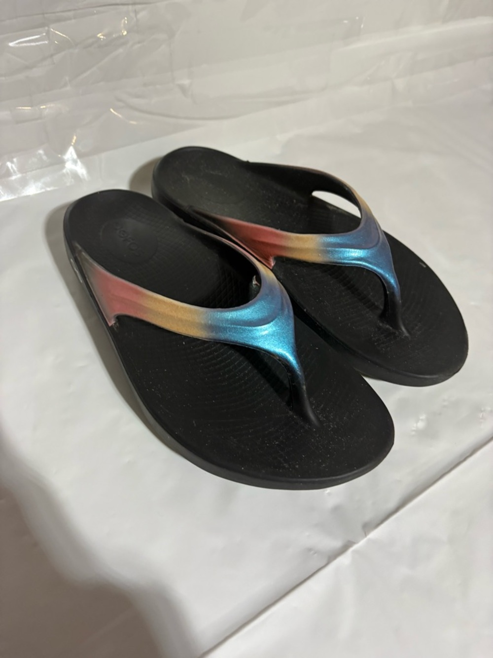OOFOS Women's Black Flip Flop Sandals with Blue, Gold, and Pink Gradient Straps